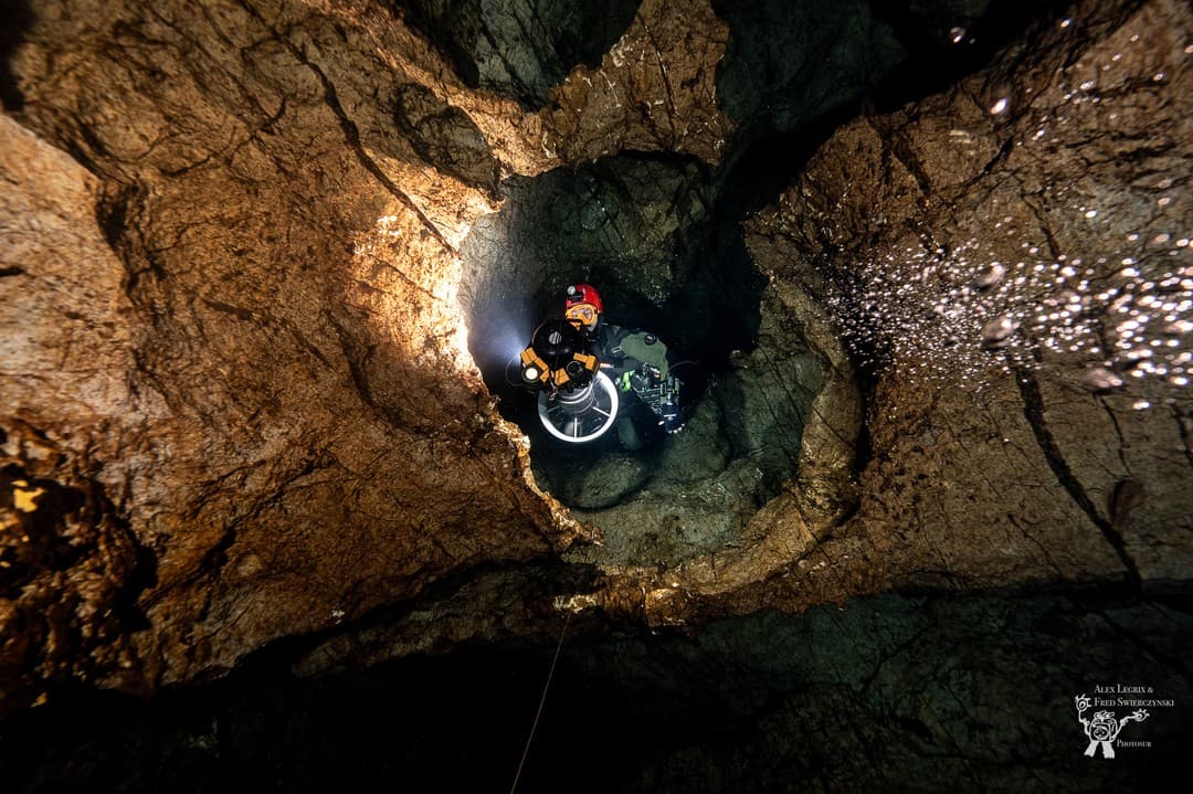 Diver in dual sidemount rebreathers in a vertical cave shaft