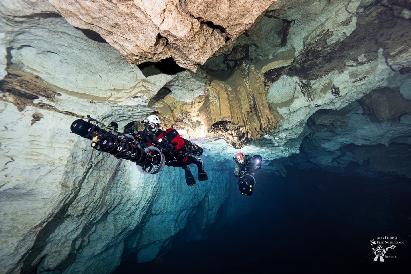 Two divers in dual Liberty Sidemount rebreathers with DPVs near cave formations