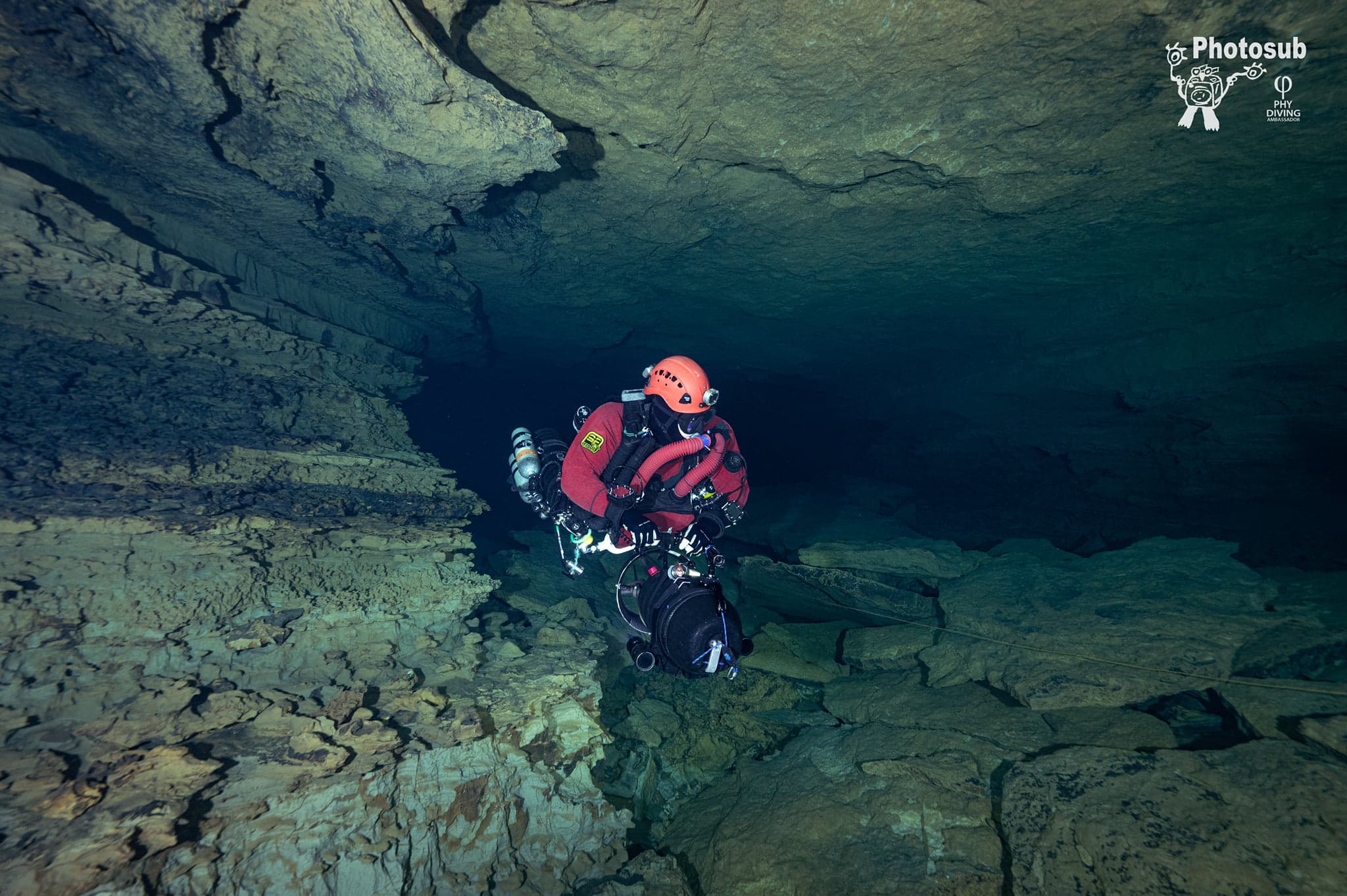 Diver in a dual rebreather configuration (a Triton and a Flex) hovering in a dark cave passage