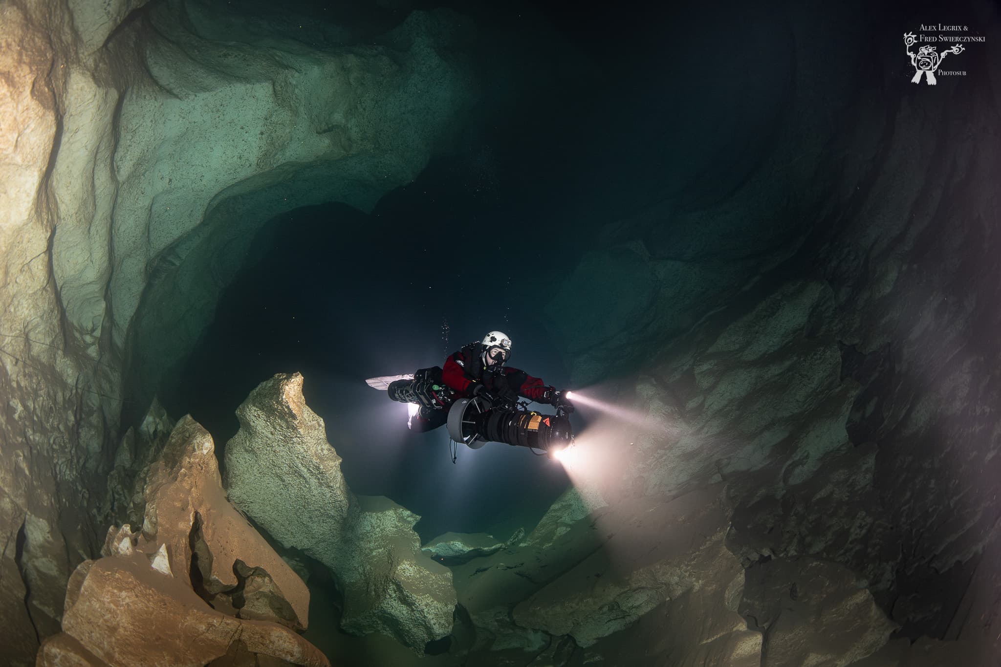 Diver in dual sidemount rebreathers riding a DPV, light beam projected ahead