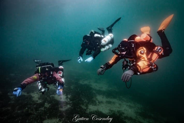 Three closed-circuit rebreather divers underwater, diving silently without exhaust bubbles