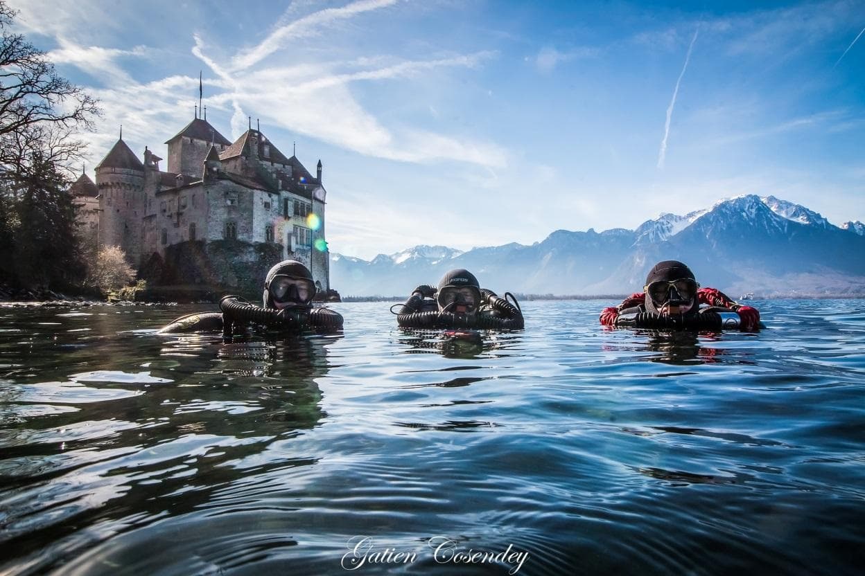 Three closed-circuit rebreather divers at the surface of an alpine lake before a dive