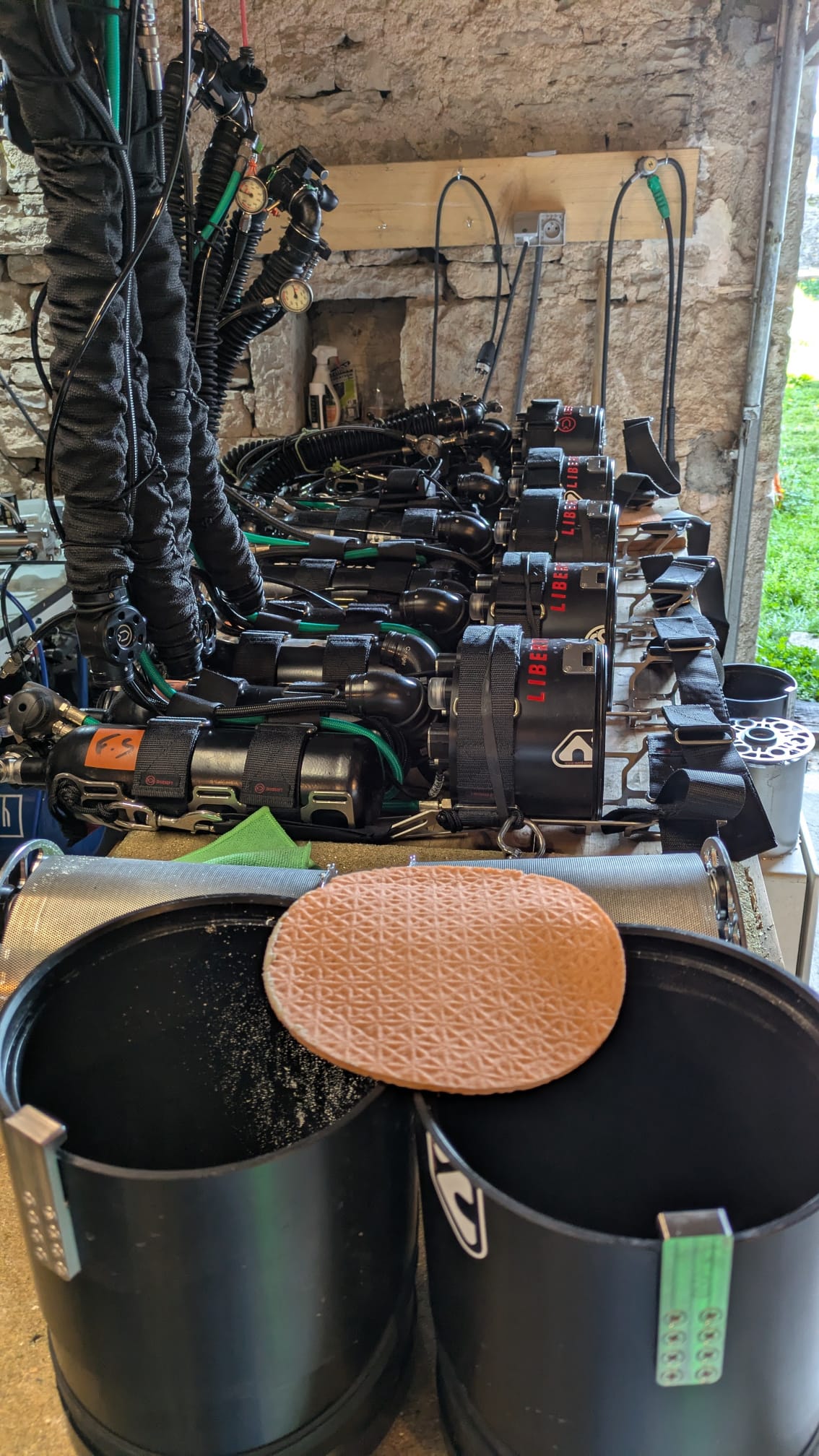 A row of sidemount Liberty units drying at a dive site after diving, with scrubber containers in the foreground