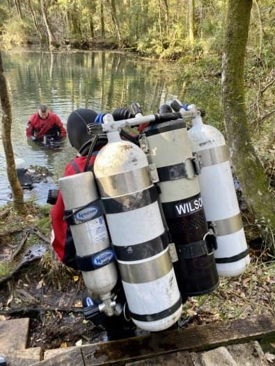 A diver on a mechanical closed-circuit rebreather with twin cylinders at a cave dive site