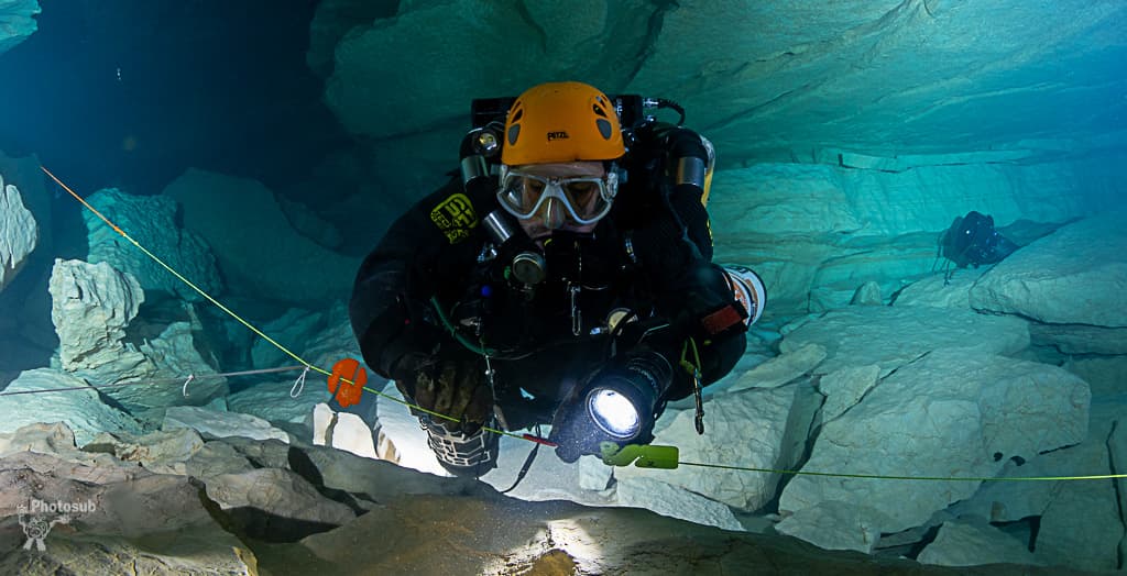 Diver placing orange cookies on the guideline at a T-junction inside a cave