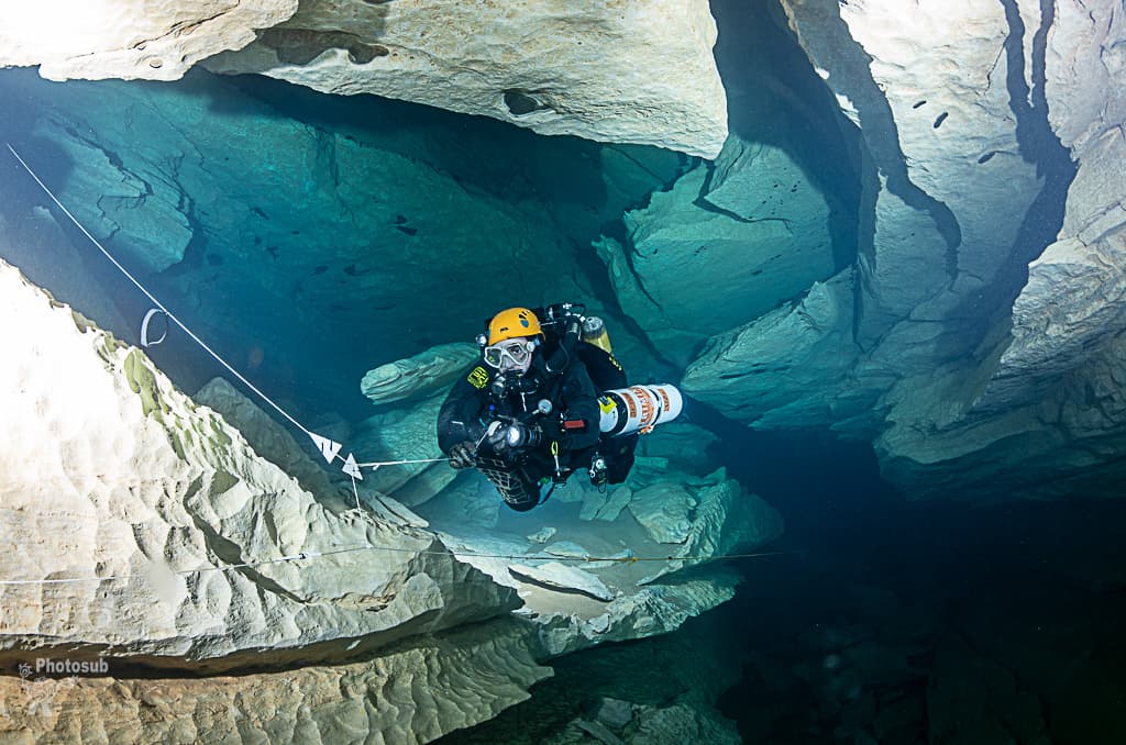 Diver with spool preparing to execute a jump, double arrow visible on the permanent guideline in open cave