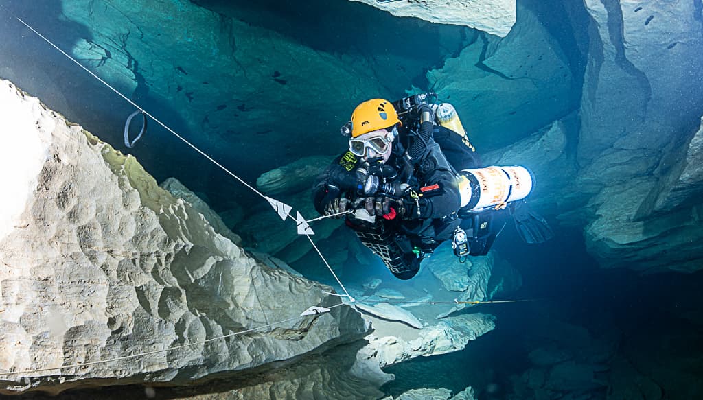 Double arrow markers on the permanent guideline indicating a jump exit point, diver holding spool