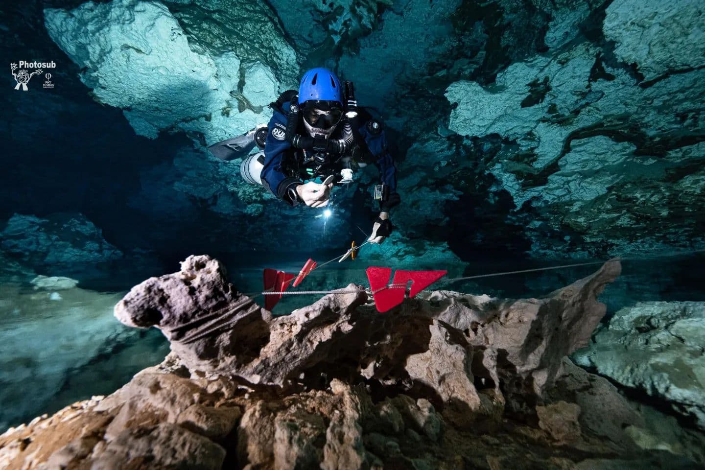 Diver following a guideline marked with red directional arrows in a cavern