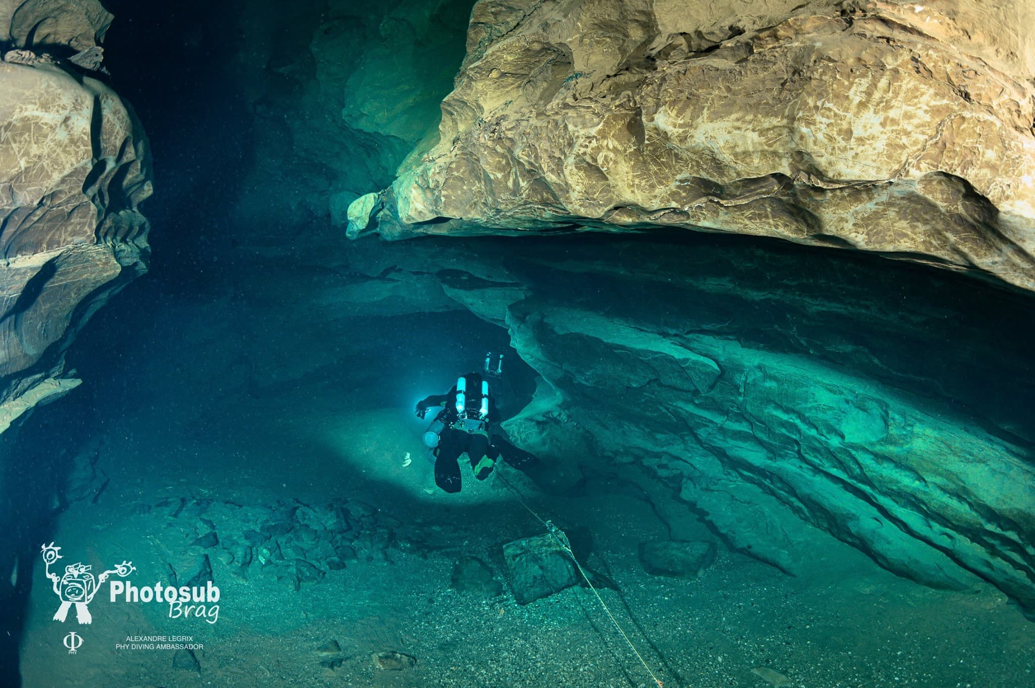Cave diver in flat horizontal trim hovering above a sandy slope in a cavern zone
